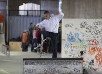 Man in white hoodie making a jump on a skateboard from a ramp