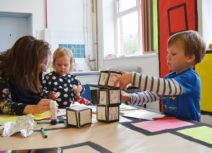 Two children and an adult creating pieces of art