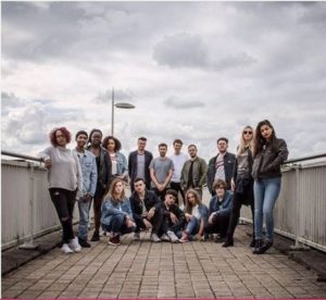 Promotional image for LEVI’S® music lab. Photo of a group of teenagers and young adults. There are railings on either side of them and they are standing outside on what appears to be a bridge over a road.