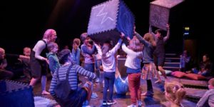 Production image from The Chit Chat Chalk Show. Children and actors are holding large black foam cubes which have been drawn on with blue chalk