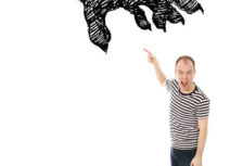 Promotional picture for Dommy B's 'Aaaagh Dinosaurs'. A man is wearing dark trousers and a black and white stripy top pointing up at a large monster's claw on a white background.