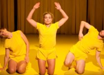 Picture of three dancers wearing yellow t-shirts and shorts
