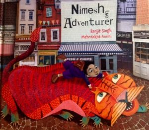 Book cover of 'Nimesh the Adventurer'. Cartoon image of a red and orange dragon with green feet, there is a girl wearing blue with brown boots riding its back and holding onto its ears.
