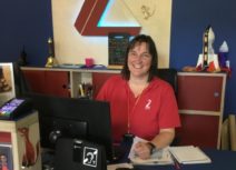 Picture of a member of box office staff wearing a red Z-arts t-shirt Z-arts' front desk