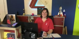 Picture of a member of box office staff wearing a red Z-arts t-shirt Z-arts' front desk