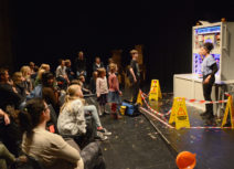 Astonishing Vacuum Cleaner Adventure production photo. A lady next to a pretend catalytic converter with young people and families going up to talk to her.