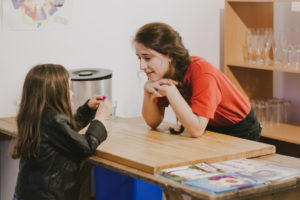 Z-arts staff member wearimg a red t-shirt talking to a girl wearing a shiny, black jacket