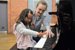 Photo of a woman and a young girl playing a grand piano