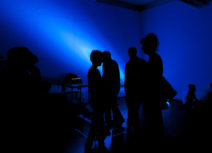 Group of people of silhouetted by dark blue light
