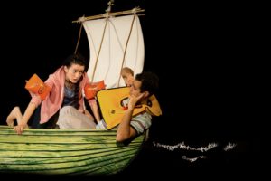 Adrift production photo. A young girl and a young boy in a boat with a sail. They are both wearing arm bands or a life jacket.