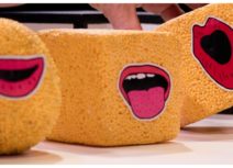 3 production images from children's Theatre Shows. 1 is of a group of children and performers standing together and dancing on stage, another is of two sponge cubes and a sponge sphere each with a pair of lips on the front, the third is of two women wearing yellow jackets and pink tshirts and standing under spotlights