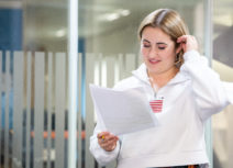 Photo of woman with brown hair wearing a white shirt holding a piece of white A4 paper
