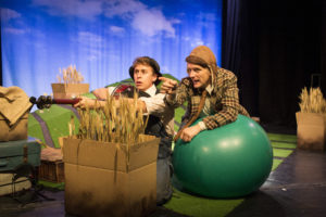 photo of two men, one is wearing a flat cap and leaning on a green yoga ball