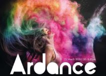 Photo of a young woman pictures in profile flipping her hair back, there is a multicoloured cloud of powder paint billowing out around her