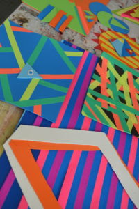 Photo of children's artwork, collection of painted abstract patterns.