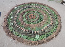 photo of a mandala pattern on the ground made from natural materials including rocks, soil and leaves