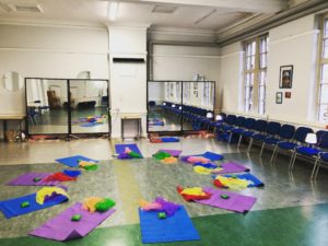 Photo of purple and blue yoga mats arranged in a circle on the floor. there are small cushions on top of the mats.