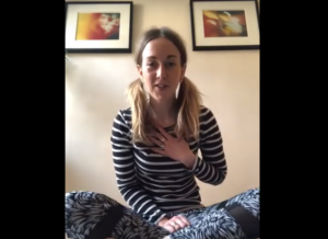Lead image for Lets Yoga. A woman wearing leggings and a long sleeved stripey tshirt is sat cross-legged looking at the camera.