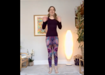 Lead image for Let's Yoga. Photo of a woman standing up wearing purple patterned leggings and a dark long-sleeved top waving at the camera.