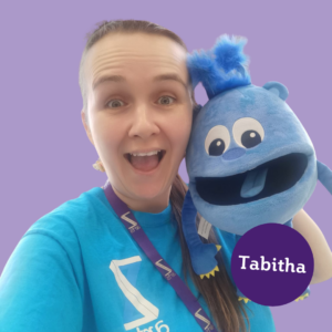 This session is led by Tabitha, Tabitha is a white woman with long brown hair. In this photo she is holding a blue monster puppet!