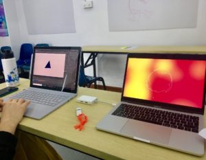 Photo of two macbooks on a desk with graphic design software on each of the screens