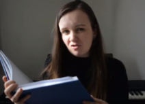 Photo of a young woman reading from a large blue book. The story is Peter Pan.
